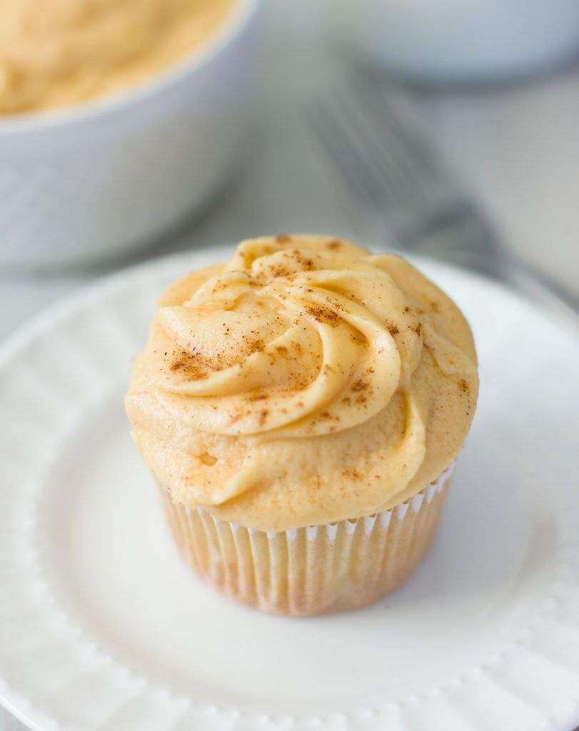 Close up look of a cupcake topped with Pumpkin Pie Frosting on a plate.