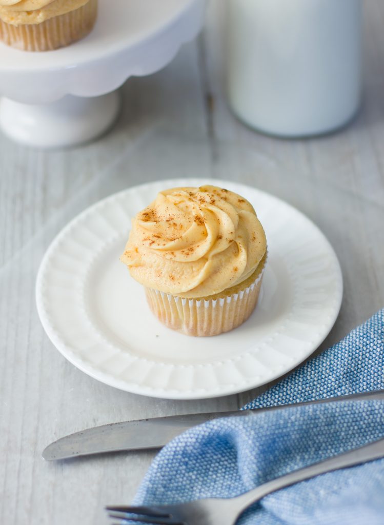 A single cupcake topped with Pumpkin Pie Frosting and sprinkled with pumpkin pie spice on a plate.