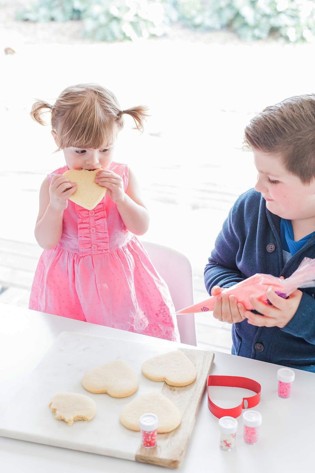 Two small children decorating cookies. 