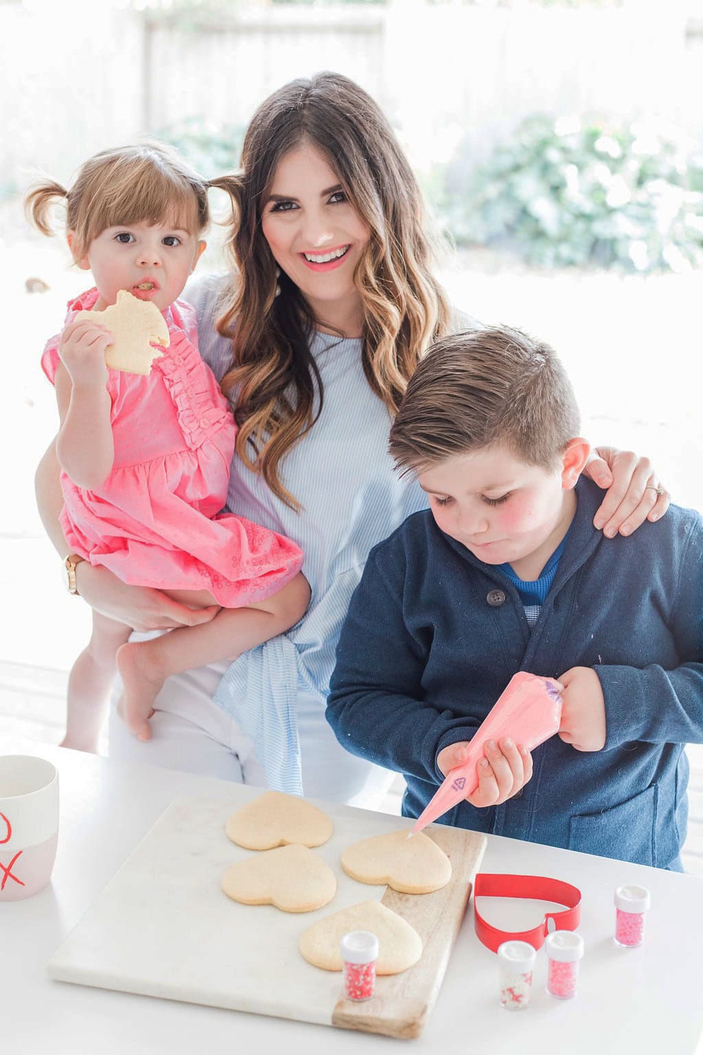 A mother and her small children decorating cookies. 