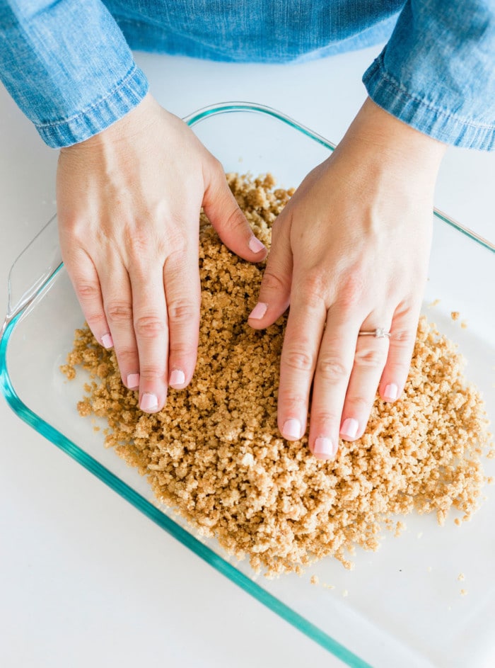 Pressing crushed graham crackers in pan for smores bars.
