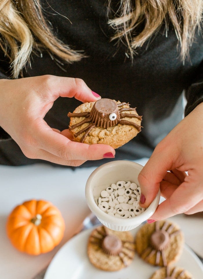 Adding candy eyes to Halloween Cookies.