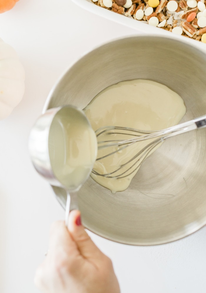 Pouring condensed milk in a bowl for pumpkin magic bars.