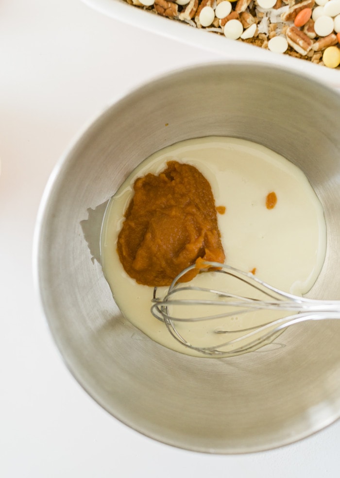Adding sweetened condensed milk and pumpkin puree in a bowl for pumpkin bar.
