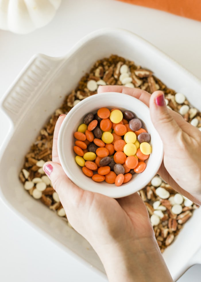 Close up look of reese's pieces in a bowl for pumpkin magic bars.
