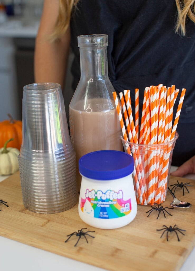 Halloween drink supplies with marshmallow creme, chocolate milk, and straws.