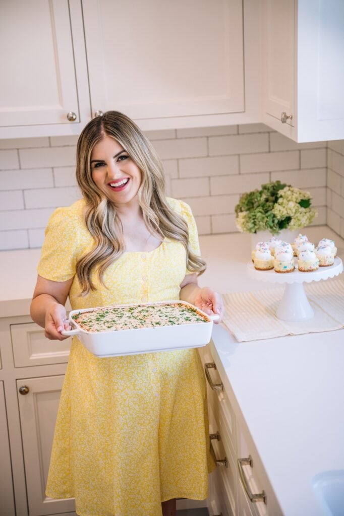 Melissa wearing a yellow dress holding her viral baked million dollar spaghetti 