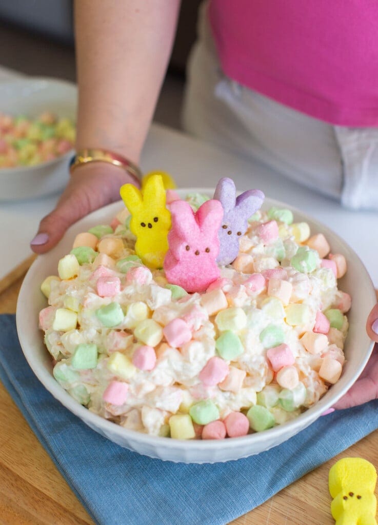 Finished Easter fluff recipe in a white bowl with pastel marshmallows and Peeps on top