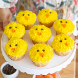 Yellow Easter chick cupcakes on a white cake stand.