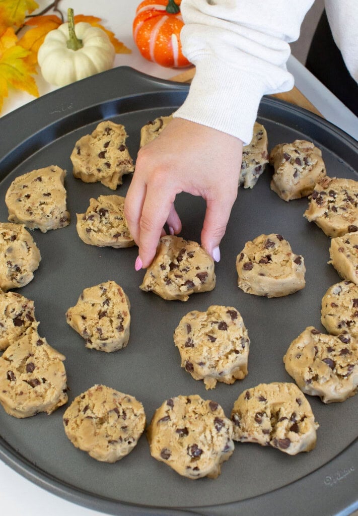 Adding cookie dough to round baking pan.