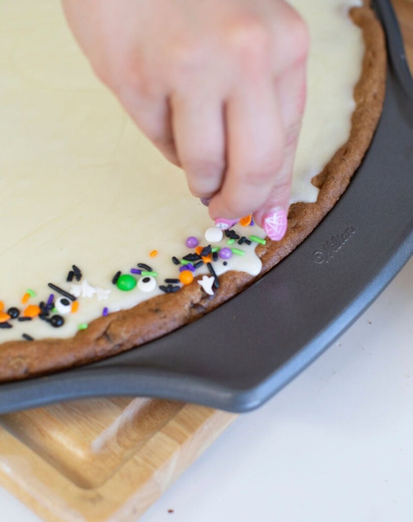 Adding sprinkles to the edge of the cookie.