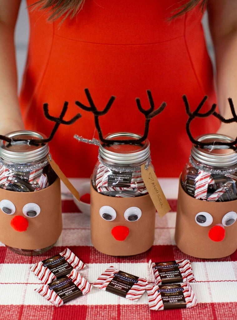 Three reindeer candy jars on a table along with a few scattered candies.