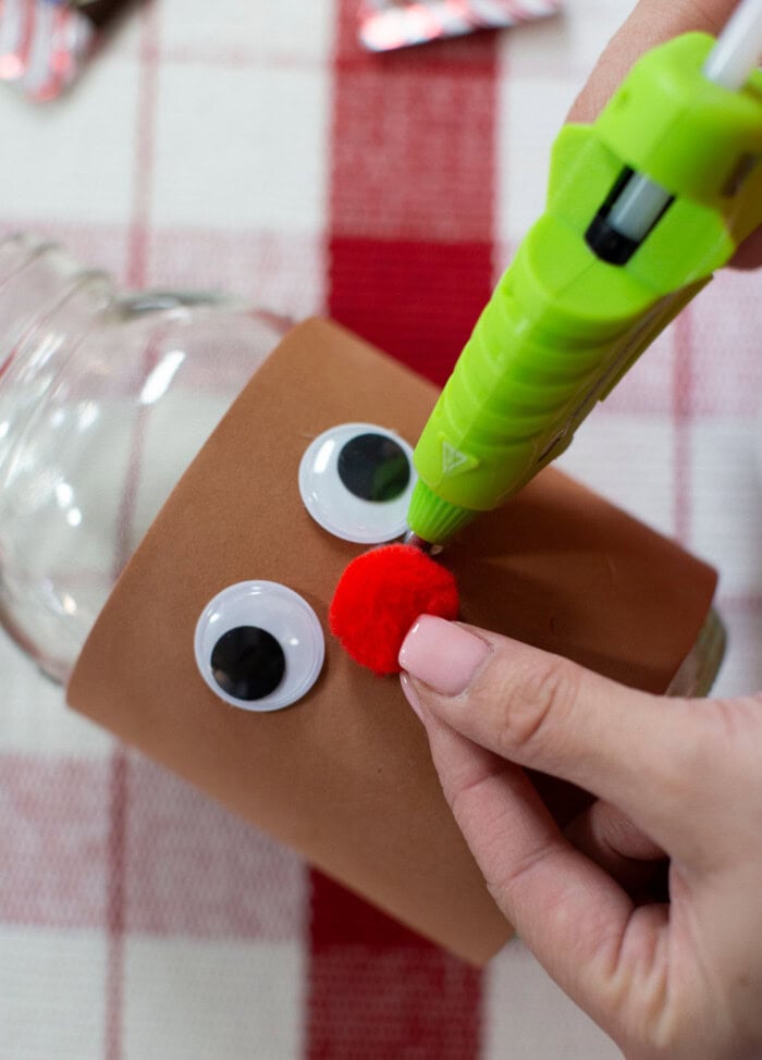 Attaching the pom-pom nose to the candy jar.