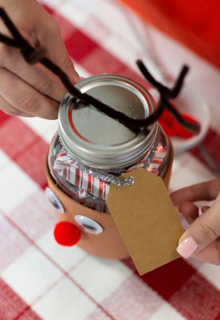 Adding a festive gift tag to the candy jar.